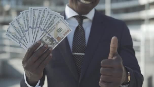 无法辨认的非裔美国人手里拿着美元，在镜头前大显身手。快乐而成功的富人在阳光下摆出一副有钱的样子.财富和商业概念. — 图库视频影像