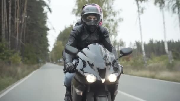 Portret van zelfverzekerde fietser rijden vriendin op de motor langs asfalt weg. Stijlvolle man die motor rijdt met een vrouw op de passagiersstoel. Begrip vrijheid en levensstijl. — Stockvideo