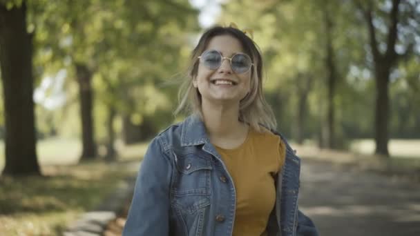 Positive young beautiful hippie woman in sunglasses smiling at camera showing peace gesture. Portrait of relaxed happy Caucasian lady in 1960s. Counterculture and lifestyle concept. — Stock Video