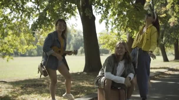 Grupo de amigos hippies positivos haciendo autostop en la soleada carretera de verano. Feliz relajado hombre y mujeres caucásicos que viajan en 1960. Mochileros disfrutando de viaje al aire libre. — Vídeo de stock