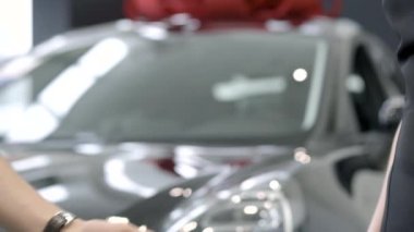 Tanımlanamayan beyaz erkek ve kadın araba anahtarlarını bayilikte dağıtıyorlar. Genç başarılı adam galeride yeni bir araç satın alıyor. Otomobil işi.