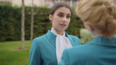 İş arkadaşıyla konuşan ve omzunu iten kızgın beyaz kadın portresi. Stresli ince hostes dışarıda iş arkadaşıyla tartışıyor. Çatışma ve turizm kavramı.