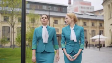 Kentin caddesinde yürüyen ve konuşan, hostes üniformalı, kendine güvenen iki beyaz kadının portresi. Zarif hostesler Avrupa 'ya geldikten sonra gezip sohbet ediyorlar. Turizm.