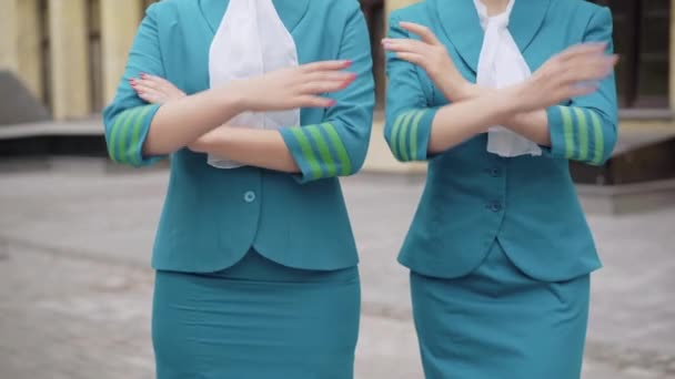 Дві нерозпізнані стрункі молоді жінки в блакитних стюардесі, що перетинають руки. Впевнені елегантні кавказькі бортпровідники, що вилітають надворі. Концепція професії та туризму. — стокове відео