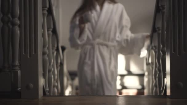 Descalza descalza mujer caucásica en albornoz blanco caminando arriba con taza de café. Retrato de una joven morena delgada por la mañana en casa o en casa de vacaciones. Estilo de vida y ocio. — Vídeos de Stock