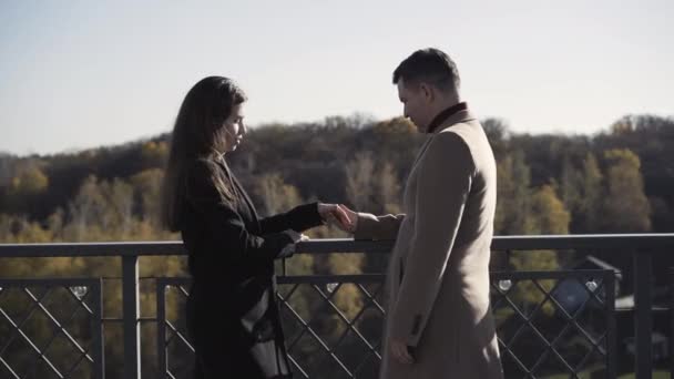 Pohled na romantický bělošský pár s věkovým rozdílem stojící na mostě za slunečného dne, držící se za ruce a mluvící. Milující muž a žena těší jarní nebo podzimní víkend venku na venkově. — Stock video