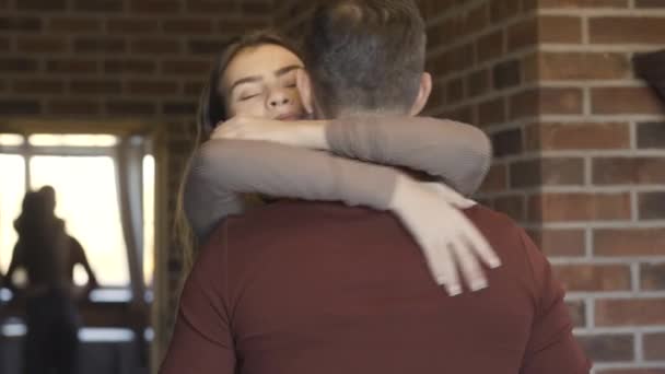 Portrait of happy beautiful young woman hugging man indoors. Brunette Caucasian charming wife or girlfriend expressing love to husband or boyfriend at home. Unity and relationship. — Stock Video