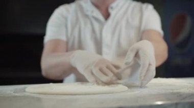Erkek aşçı restoran mutfağında pizza hamuru yapıyor. Ulusal İtalyan yemeklerini içeride pişiren eldivenli, tanınmayan beyaz adam. Şef pizzacıda çalışıyor. Mutfak ve mutfak..