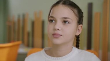 Sınıfta oturan ve konuşan güzel beyaz bir kızın yakın plan portresi. Devlet okulunda kendine güveni tam bir liseli kız. Öğrenim ve eğitim kavramı.