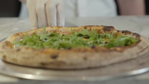 Close-up van vers gebakken smakelijke pizza in de keuken van het restaurant, Man Kaukasische hand in hand handschoen duwen heerlijk smakelijk eten voor de camera. Onherkenbare man met maaltijd in pizzeria. — Stockvideo