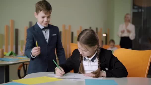 Écolier mignon donnant crayon à jolie écolière et souriant. Portrait d'enfants caucasiens charmants étudiant à l'école publique. Concept d'éducation et d'amitié. — Video
