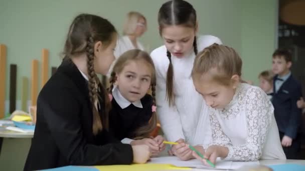 Gruppo di studentesse intelligenti che discutono il progetto di lavoro di squadra in classe con compagni di classe sfocati e insegnanti che parlano sullo sfondo. Ragazze concentrate che studiano insieme a scuola. — Video Stock