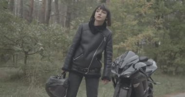 Yol kenarında otostop çeken üzgün, beyaz, güzel bir kadının portresi. Kırık motosikletli genç bayan yarışçı ayakta ve dışarıda el kol hareketi yapıyor. Sinema 4k ProRes Merkezi.