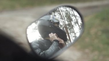 Motosiklet kaskı takan kendine güvenen genç adamın dikiz aynasında yansıması. Kendine güvenen Ortadoğulu yarışçı bir sürüş için hazırlanıyor. Yarış ve adrenalin konsepti.