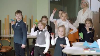 Pozitif okul çocukları sınıfta kağıt uçaklar fırlatıp alkışlıyorlar. Bir grup neşeli öğrenci, liseli kız ve öğretmen devlet okulunda okurken eğleniyorlar. Eğitim ve yaşam tarzı.