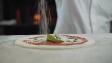 Tanımlanamayan Kafkasyalı aşçı restoranda çiğ pizzaya rendelenmiş peynir döküyor. Erkek aşçı mutfakta yemek pişiriyor. Pizzacıda çalışan eldivenli profesyonel bir adam..