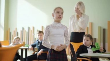 Devlet okulunda ders sırasında sınıf arkadaşları ve öğretmenlerle konuşan akıllı kız öğrencinin portresi. Kafkasyalı kendine güvenen bir kız içeride hikaye ya da şiir anlatıyor. Eğitim ve Edebiyat.