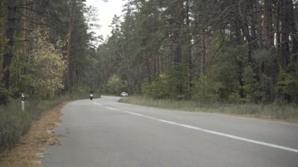 Extreme wide shot of man riding motorcycle to camera. Confident young man in leather jacket and helmet driving motorbike along the road outdoors. Lifestyle and racing concept. — Stock Video