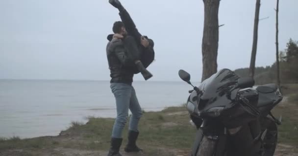 Bonito motociclista alegre girando namorada na margem do rio. Ampla foto de casal interracial feliz se divertindo como namoro ao ar livre. Conceito de amor e relacionamento. Cinema 4k ProRes HQ. — Vídeo de Stock