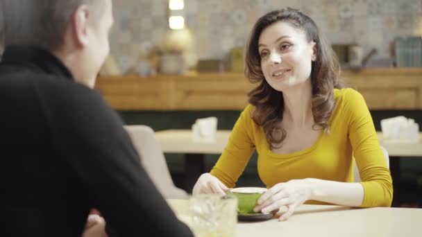 Portræt af charmerende smuk kaukasiske kvinde taler til uigenkendelig mand sidder i restaurant og smilende. Positiv smuk voksen kæreste dating med kæreste i pizzeria. – Stock-video
