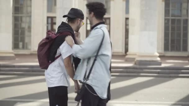 Amici millenari moderni spensierati che danno il cinque, abbracciano e guardano la macchina fotografica. ritratto di positivo caucasico giovani uomini e donne che si incontrano sulla strada soleggiata della città all'aperto e posa. — Video Stock