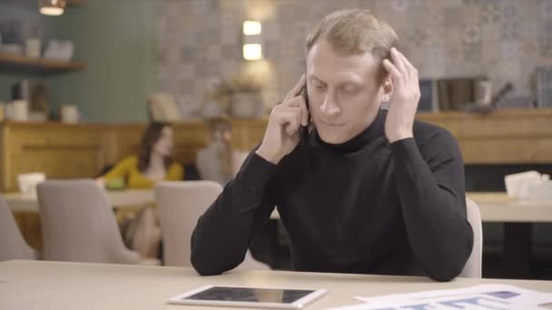 Portrait d'un homme d'affaires caucasien stressé parlant au téléphone au restaurant, accrochant son smartphone et tenant la tête dans les mains. Un bel homme inquiet qui bosse trop au déjeuner. Concept d'entreprise. — Video