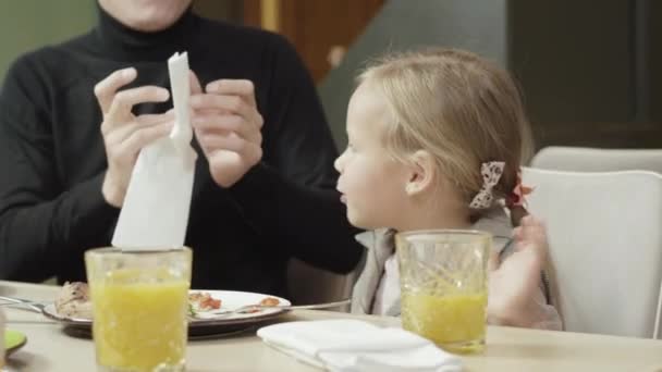 Oigenkännlig far och söt dotter städa händer och ansikte efter middag i pizzeria. Charmig vit tjej och suddig man som äter på restaurang. Familj fritid och livsstil koncept. — Stockvideo