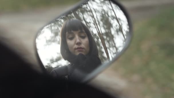 Refleksi wanita Kaukasia yang cantik mengoleskan lipstik di kaca spion belakang sepeda motor. Biker wanita muda yang menarik berdandan di luar ruangan. Konsep kecantikan dan gaya hidup. — Stok Video