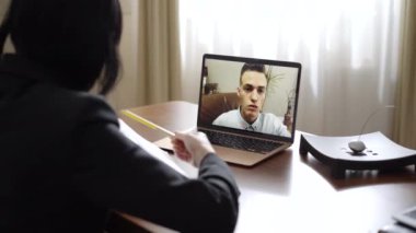 Tanımlanamayan kadın psikolog kağıtlara bakıyor ve bilgisayardaki depresif adamla konuşuyor. Profesyonel beyaz kadın görüntülü sohbet kullanarak hastaya danışmanlık yapıyor..