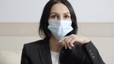 Kapalı mekandaki kameraya bakan kendine güvenen profesyonel kadın psikolog. Coronavirus salgını için ofiste poz veren güzel bir uzmanın portresi.