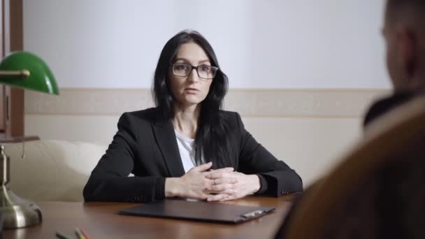 Femme caucasienne confiante dans les lunettes parler à l'homme assis dans le bureau de psychologue. Portrait de femme spécialiste consultant patient déprimé à l'intérieur. Aide psychologique professionnelle. — Video