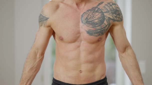 Trunchiul tatuat gol al unui tânăr sportiv muscular din Orientul Mijlociu care ridică gantere. Antrenament atletic de nerecunoscut care lucrează acasă în interior. Exercitarea și conceptul de masculinitate. Slowmo . — Videoclip de stoc