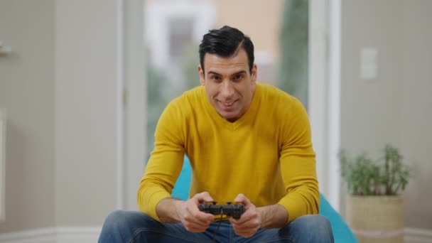 Portret szczęśliwego, beztroskiego człowieka z Bliskiego Wschodu, używającego konsoli do gier wideo. Zrelaksowany uśmiechnięty gracz grający w domu. Koncepcja stylu życia i uzależnienia od gier. Zwolniony ruch. — Wideo stockowe