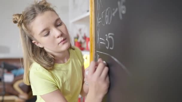 Zseniális kaukázusi lány portréja, aki matekfeladatot old meg a táblán az iskolában. Okos, intelligens iskolás lány, aki matematikát tanul idebent. Oktatás és intelligencia a Z generációban. — Stock videók