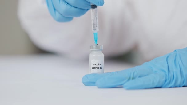 Doktorların mavi eldivenlerle yakın plan çekimleri Covid-19 aşı ampulü ve şırınga pompalama iğnesi. Coronavirus viral enfeksiyonundan muzdarip insanları tanımayan tıbbi aşı.. — Stok video