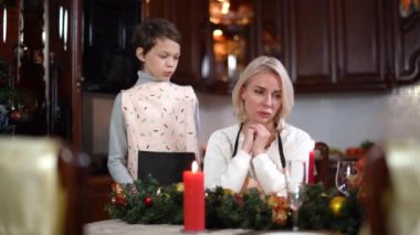 Neşeli küçük çocuk güzel genç bir kadınla konuşuyor ve annesine sarılıyor. Evde Noel arifesini kutlayan pozitif beyaz bir ailenin portresi. Yeni yılda yalnız ebeveyn ve çocuk.