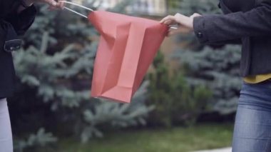 İki tanınmayan kadının alışveriş yaptığı bir alışveriş çantasına yakın çekim. Açık havada satın almak için savaşan kendine güvenen beyaz kadınlar. Alışveriş ve bağımlılık kavramı.