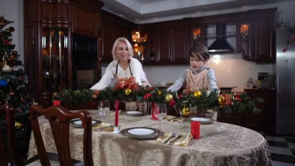 Portret împușcat cu mama și fiul caucazian vesel punând decorațiuni de Crăciun pe masă și dând high-cinci. Fericit blonda femeie și bruneta baiat having distracție pregătirea pentru Anul Nou sărbătoare . — Videoclip de stoc