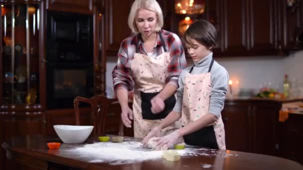 Сыну и матери весело месить тесто дома на кухне. Позитивный кавказский мальчик и женщина готовят в помещении, трогая носы мукой. Веселая семья наслаждается выпечкой. Кулинарная концепция. — стоковое видео