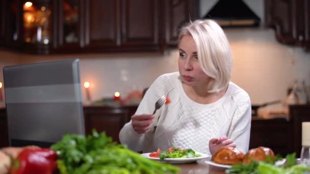 Spěchá mladá žena na večeři, surfuje na internetu na notebooku a mluví po telefonu. Portrét moderní bělošky kombinující oběd a obchod doma. Koncept rovnováhy života. — Stock video
