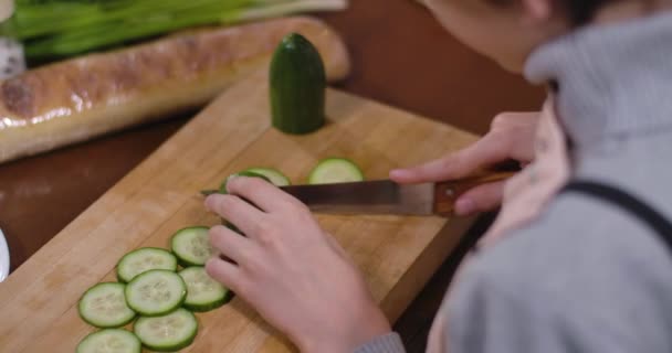 Onherkenbare jongen die komkommer snijdt voor gezonde salade. Hoge hoek uitzicht op kind koken gezond eten in de keuken thuis. Moeders hand nemen plakjes om te proeven. Cinema 4k ProRes Hoofdkwartier. — Stockvideo