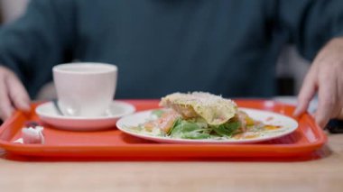 Erkek kıdemli eller kafeteryadaki masada lezzetli bir kahvaltı tepsisi taşıyor. Kafe veya restoranda yemek yiyen tanınmamış Kafkasyalı emekliler. İçeride öğle yemeği yiyen bir adam..