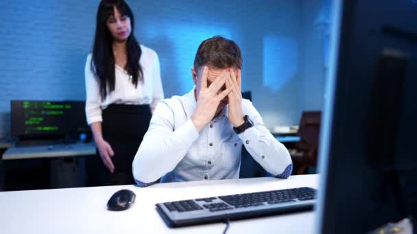 Hombre agotado frotando la cara como mujer nerviosa gritando y haciendo gestos en el fondo en la oficina azul. Joven dama caucásica regañando a un tipo en el interior. Retrato del hacker programador cansado y jefe. — Vídeos de Stock