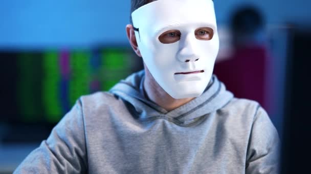 Young brunette man in face mask hacking website indoors. Portrait of unrecognizable Caucasian hacker doing cyber attack indoors typing codes on keyboard. Computer system safety. — Stock Video