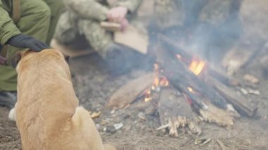 Tanımlanamayan bir asker kadın köpeğinin kafasını ateşle okşuyor ağır çekimde yanıyor ve askerler etrafta oturuyor. Poligon ya da ana kampta acemiler..