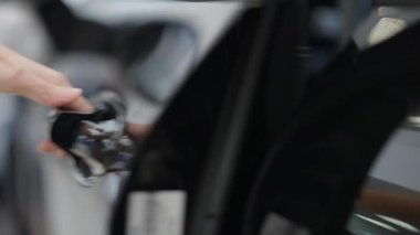 Sıska, genç bir kadın, araba kapısını açıyor ve kendine güvenen bir iş kadını sürücü koltuğunda oturuyor. Tanımlanamayan beyaz kadın galeriden araç alıyor. Başarı ve yaşam tarzı.