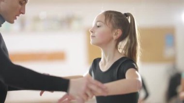 Konsantre kız dans stüdyosunda öğretmeninin yardımıyla bale provası yapıyor. Kapalı alanda klasik dans eğitimi alan yetenekli beyaz çocuklar. Profesyonel öğretmenlik çocukları. Sanat ve beceri kavramı