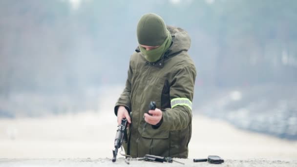 Soldado caucásico concentrado profesional desarmando pistola estriada y bajando el arma. Retrato de recluta masculino entrenando al aire libre en polígono. Concepto militar. — Vídeos de Stock