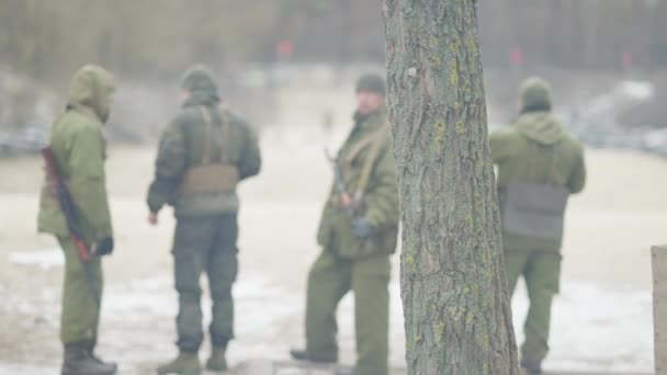 Visão ampla de quatro militares armados em pé ao ar livre no outono ou no polígono da primavera. Soldados profissionais caucasianos na linha da frente. Estilo de vida militar. — Vídeo de Stock