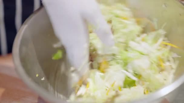 Close-up of female hand in white glove mixing healthful vegetable salad in metal bowl. Unrecognizable cook working in cafeteria or dining room. Woman preparing healthy eating in kitchen. Slow motion. — Stock Video